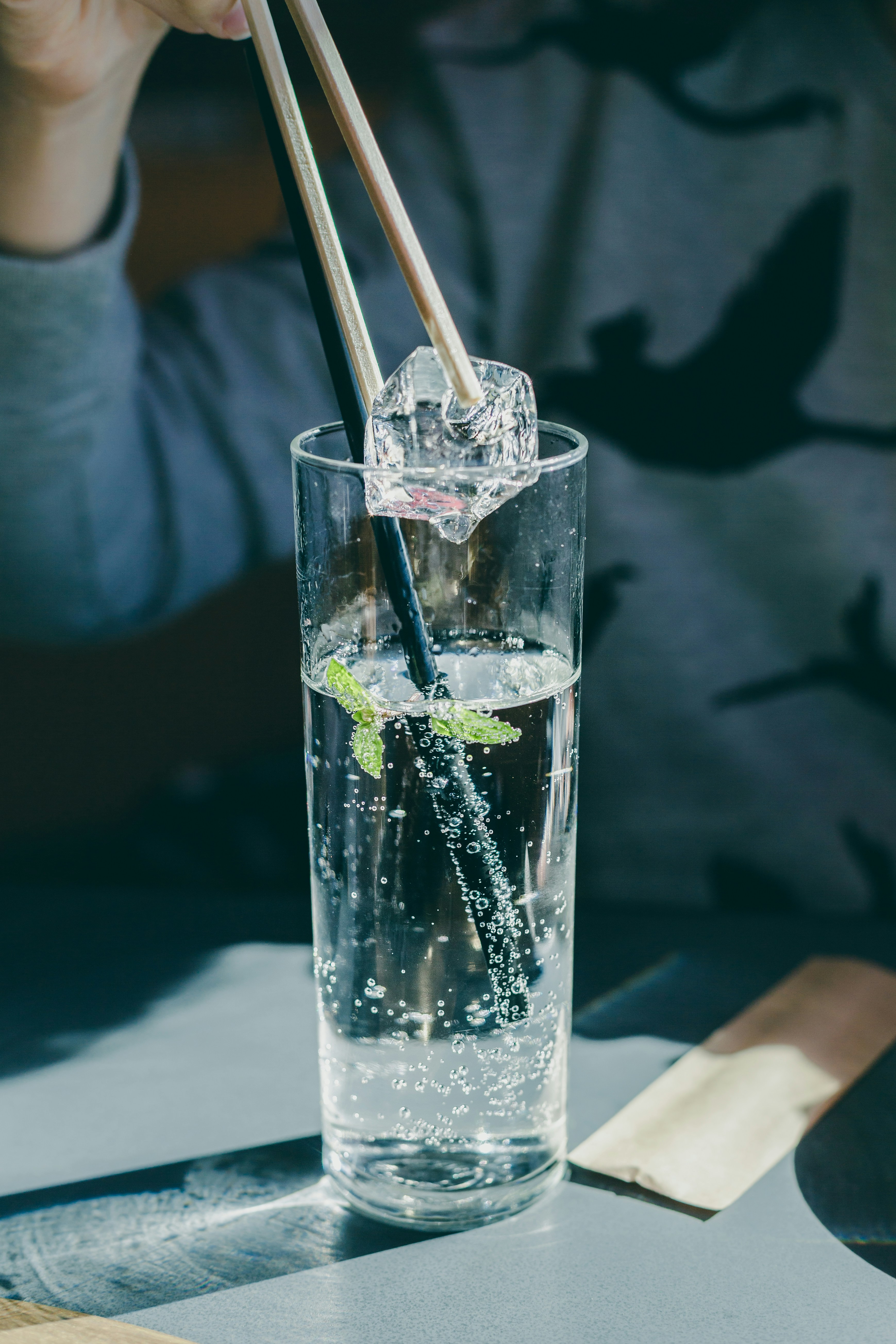 A glass of sparkling water with lime next to a crystal tumbler
